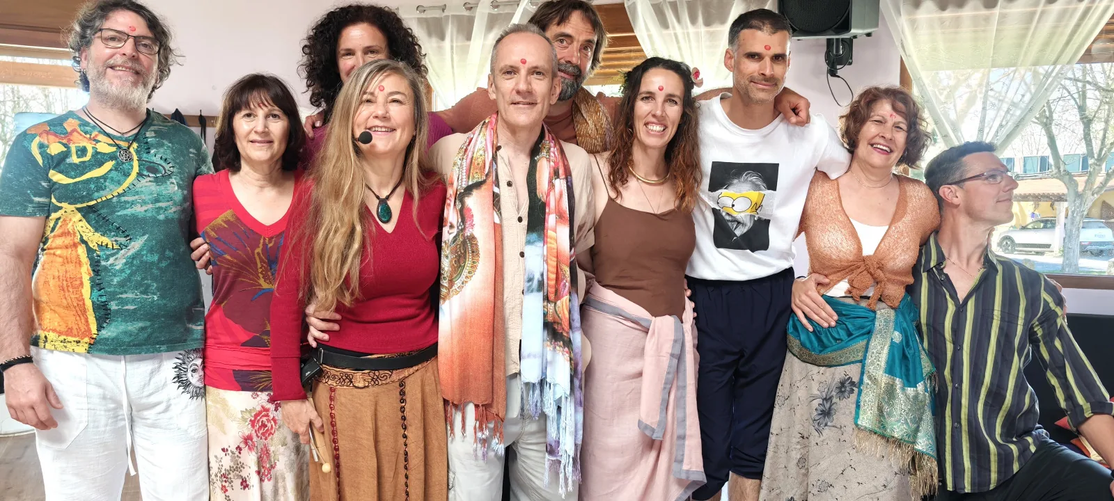 El equipo de facilitadores sonriendo abrazados en grupo en una sala luminosa.